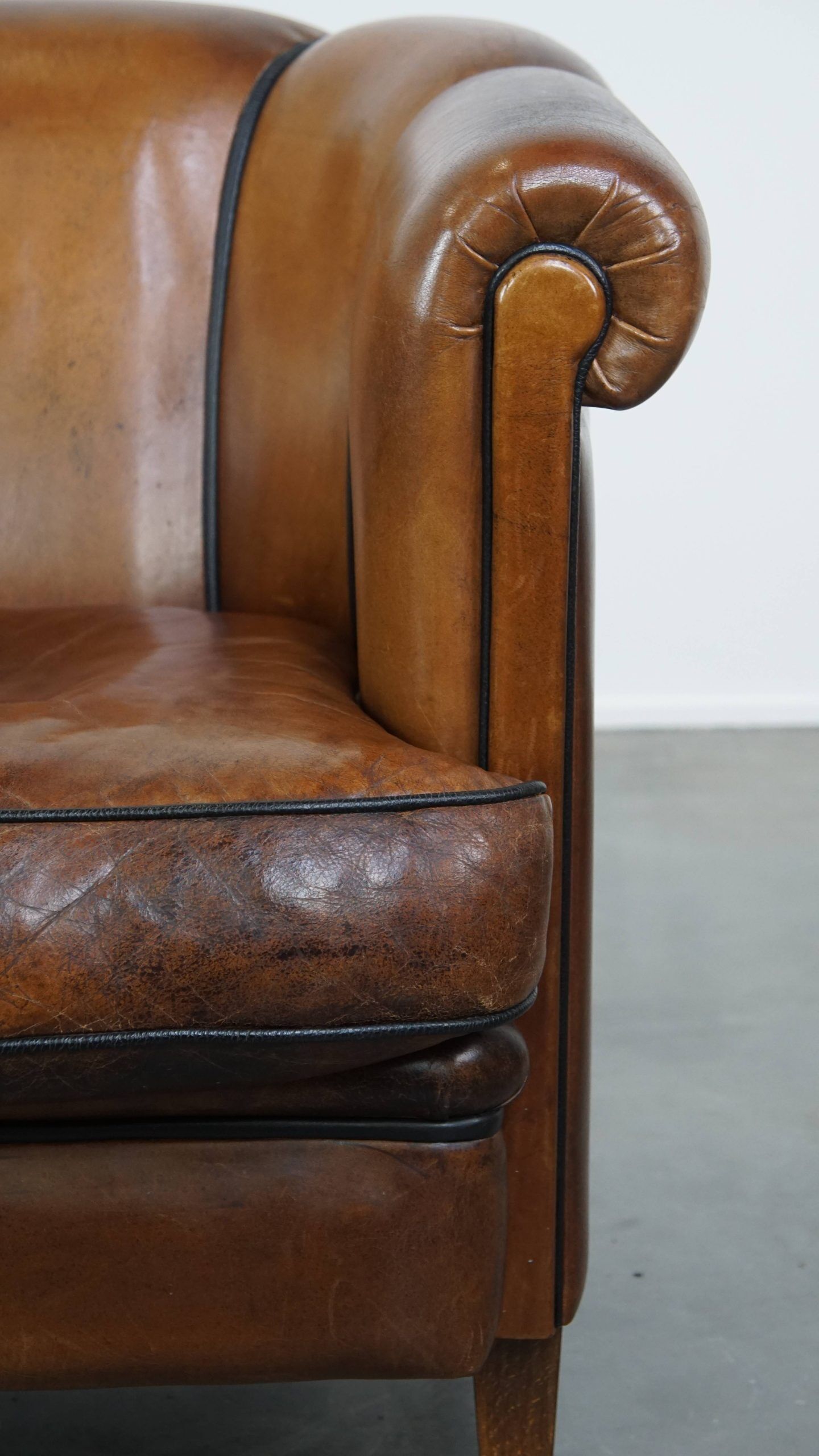 Unique vintage cognac-coloured leather club armchair with black piping