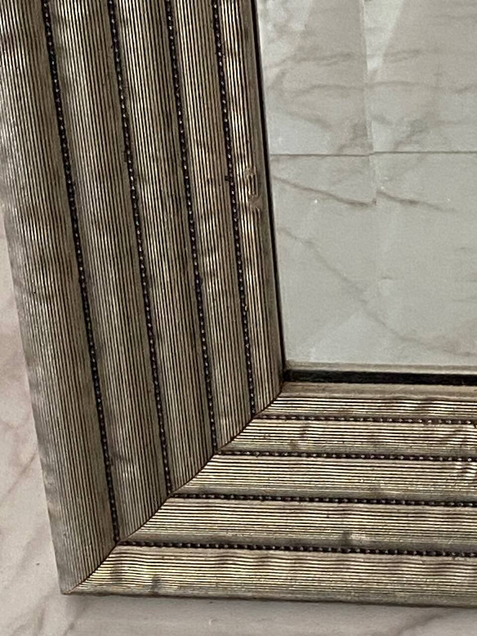 Textured embossed metal wall mirror with bevelled mirror.