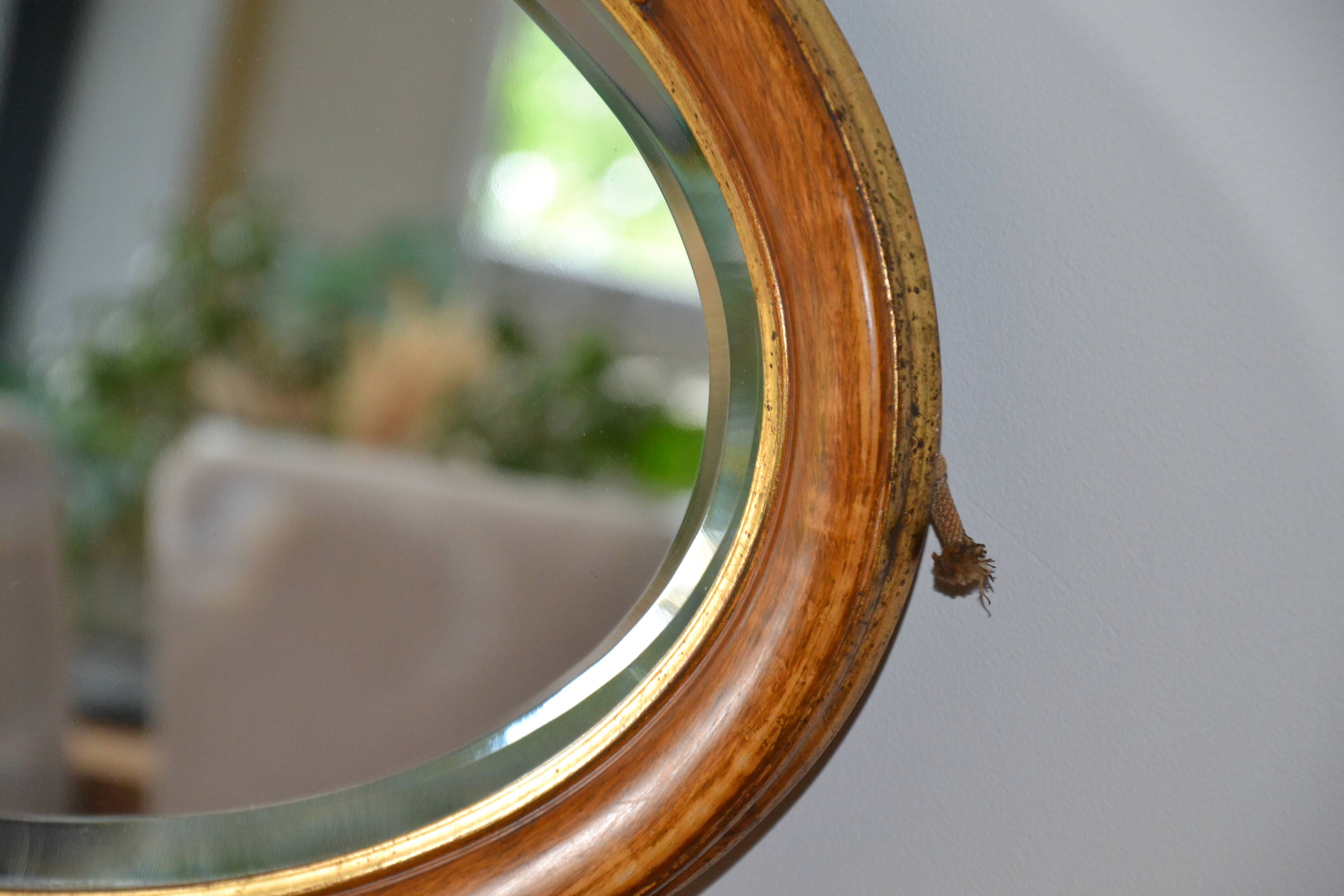 Old oval beveled wooden mirror, partly gilded and carved