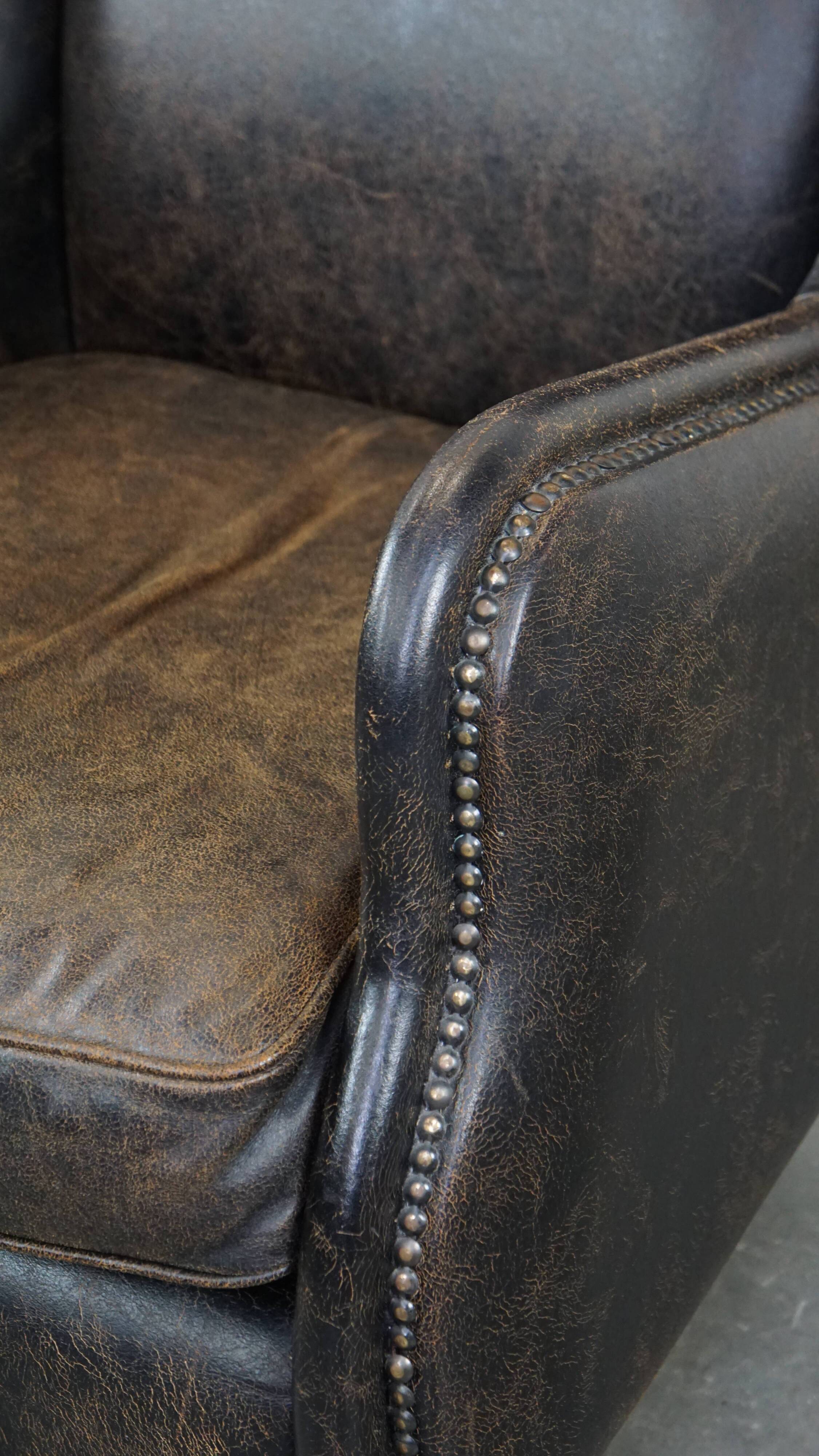 Black cow leather armchair finished with decorative nails, industrial style