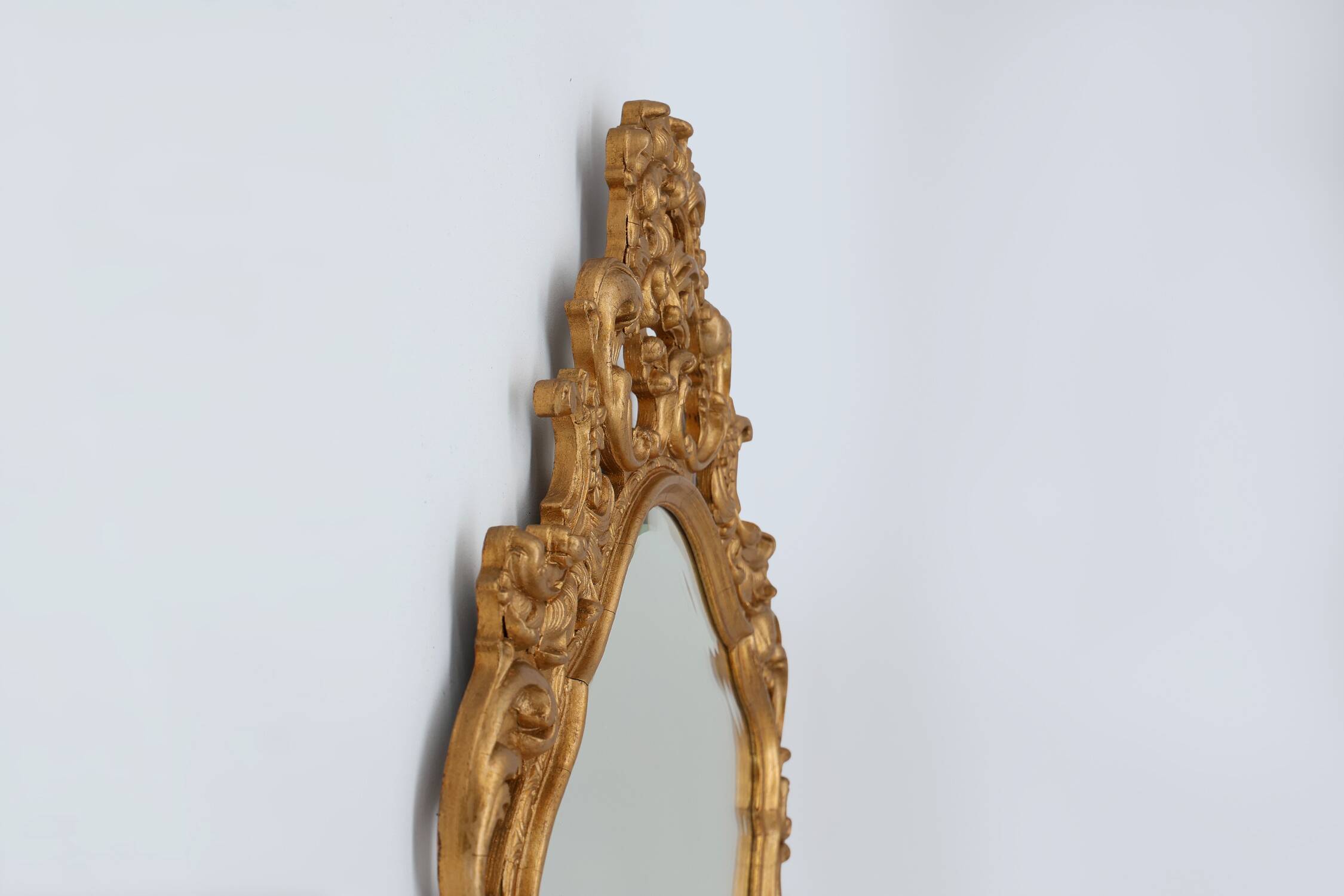 French Rococo or Baroque style facet-cut crest mirror in gilded carved wood