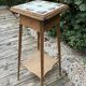 Antique wooden plant stand with ceramic tiles.