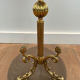 A round, neoclassical-style brass side table with a base decorated with dolphins and a red celluloid top encircled by an openwork gallery, attributed to the House of Jansen.