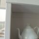 Shallow depth bookcase re-enchanted in pearl gray, wooden shelves.