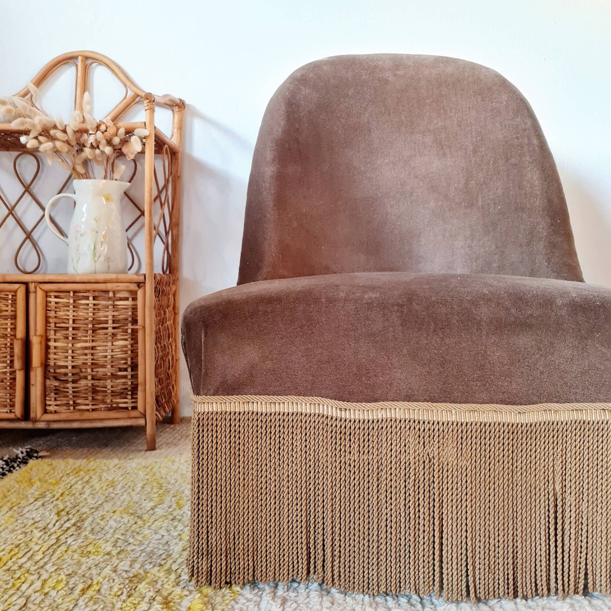 Brown velvet crapaud armchair with fringes and sculpted legs.