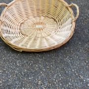 Round presentation basket made of woven wicker and rattan.