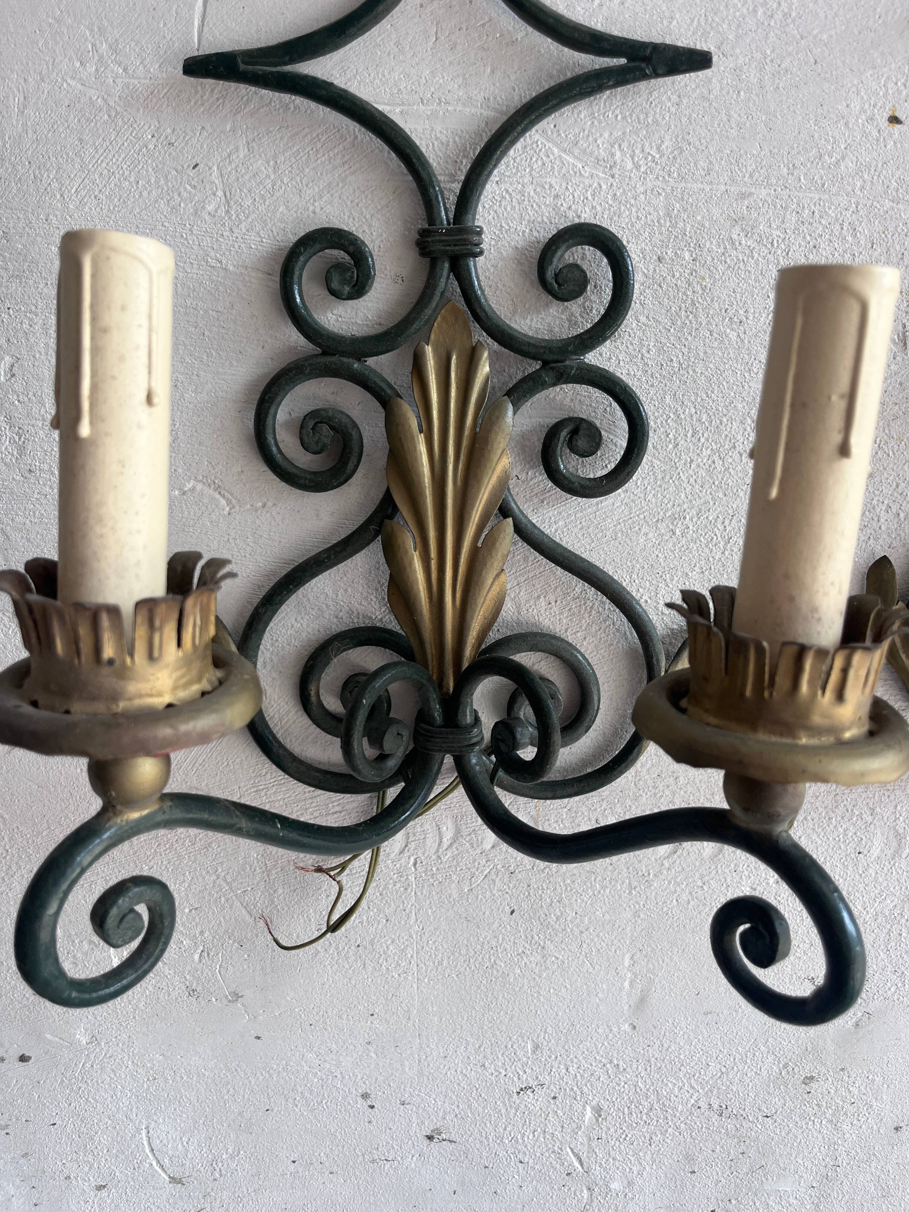 Pair of wall sconces in wrought iron with golden leaf patterns.