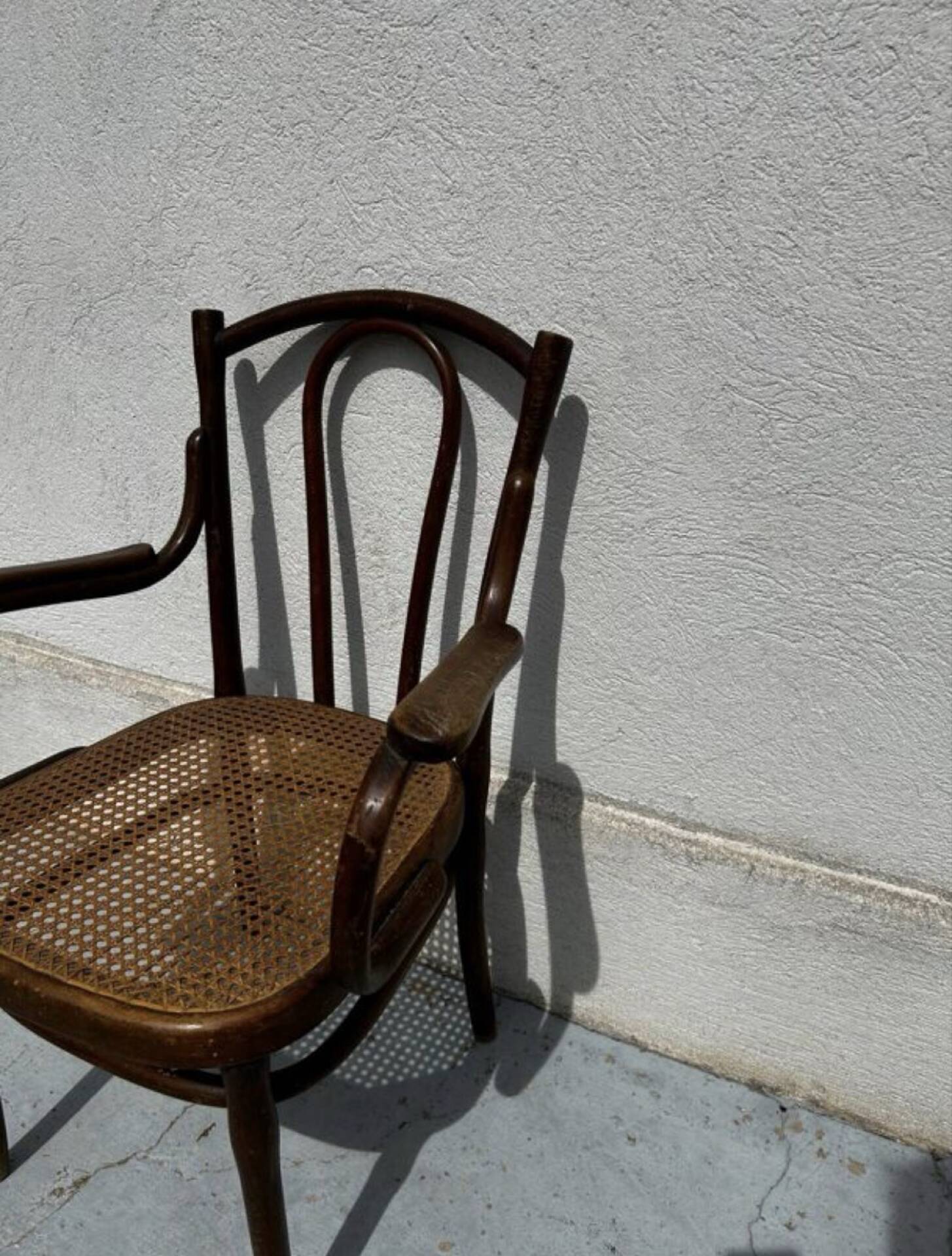 Thonet armchair stamped with curved wooden armrests and caning from the 19th century.
