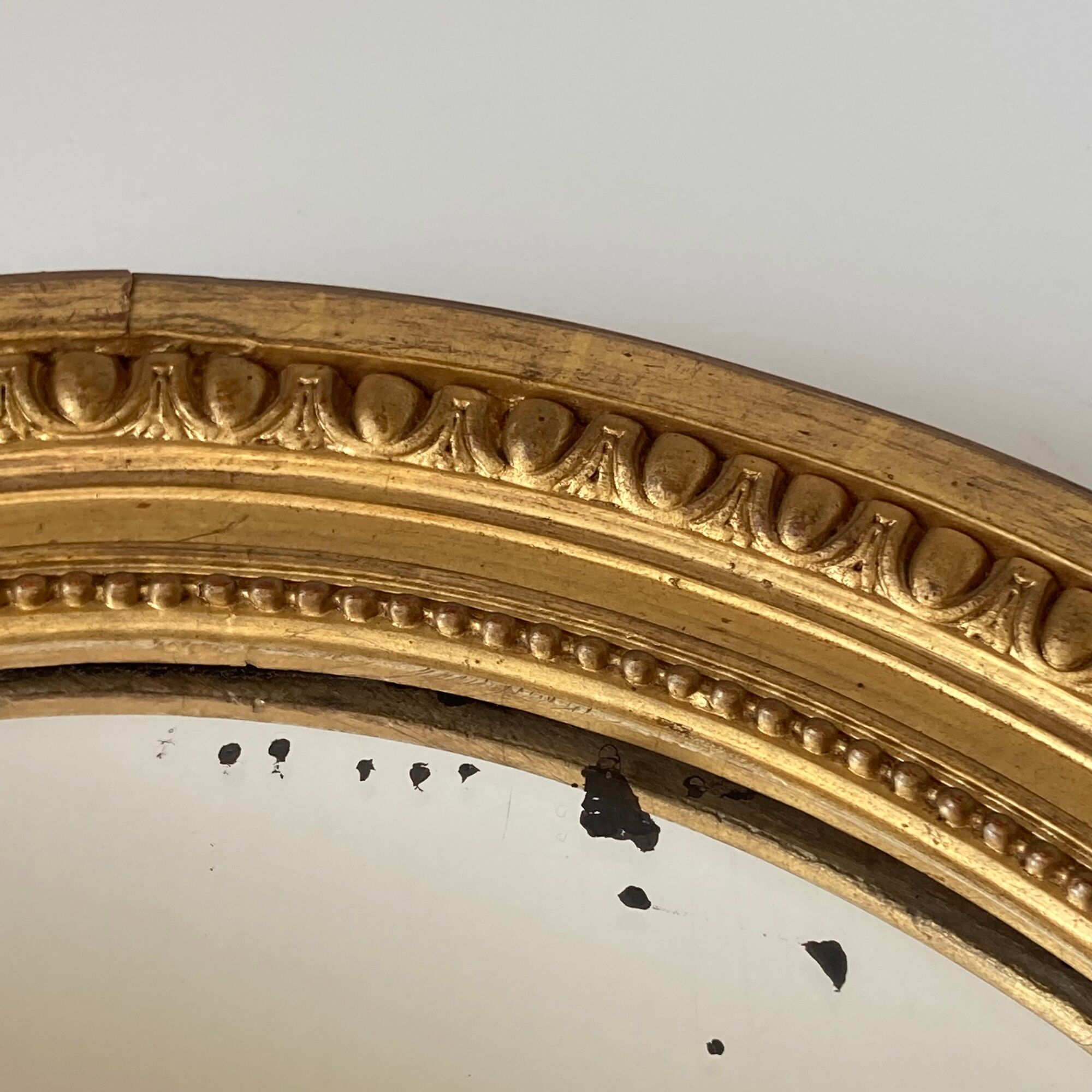 Oval mirror in carved wood, stuccoed and gilded with leaf Louis XVI style late nineteenth century
