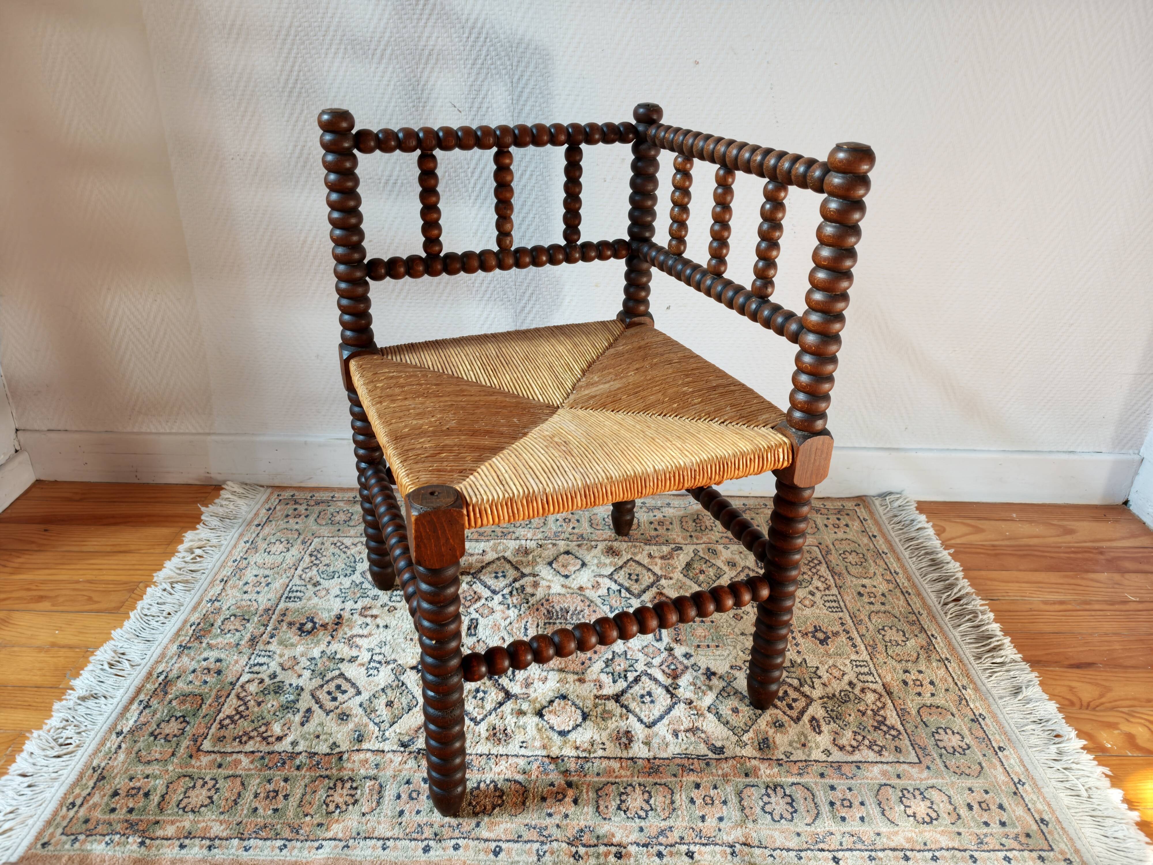 Old wooden turned spindle fireside chair with a straw seat.