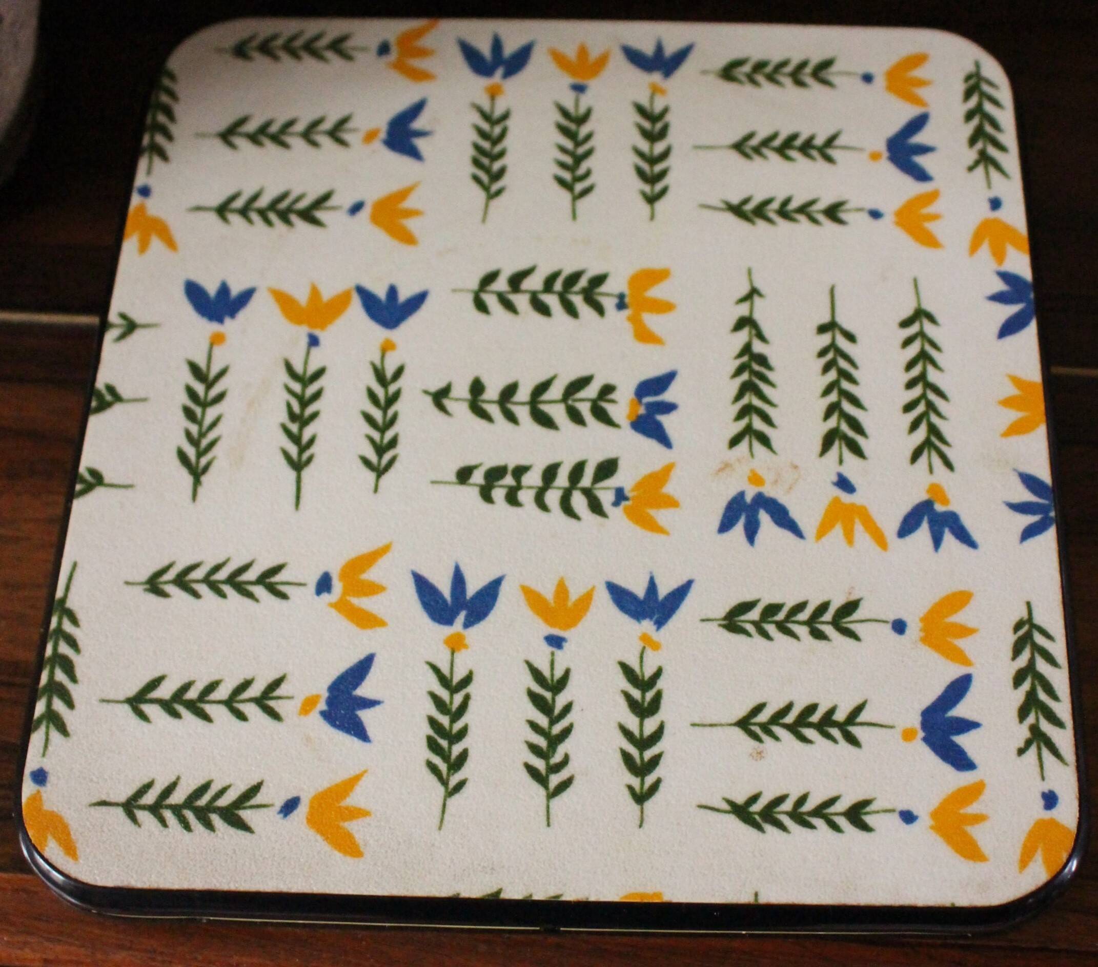 Vintage laminated wooden trivet with yellow, green, and blue flowers