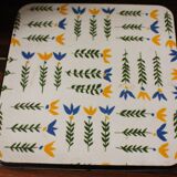Vintage laminated wooden trivet with yellow, green, and blue flowers