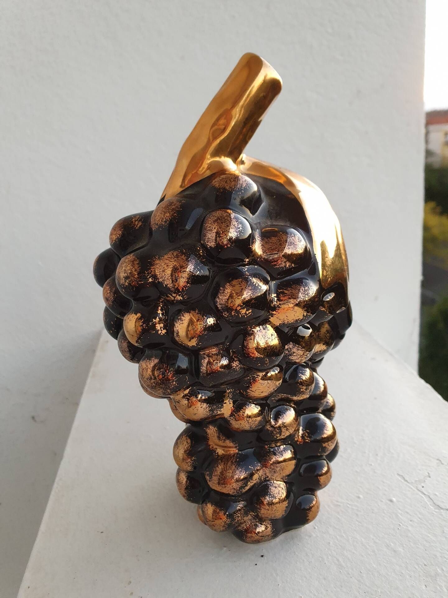 Beautiful black and gold ceramic bottle in the shape of a bunch of grapes.