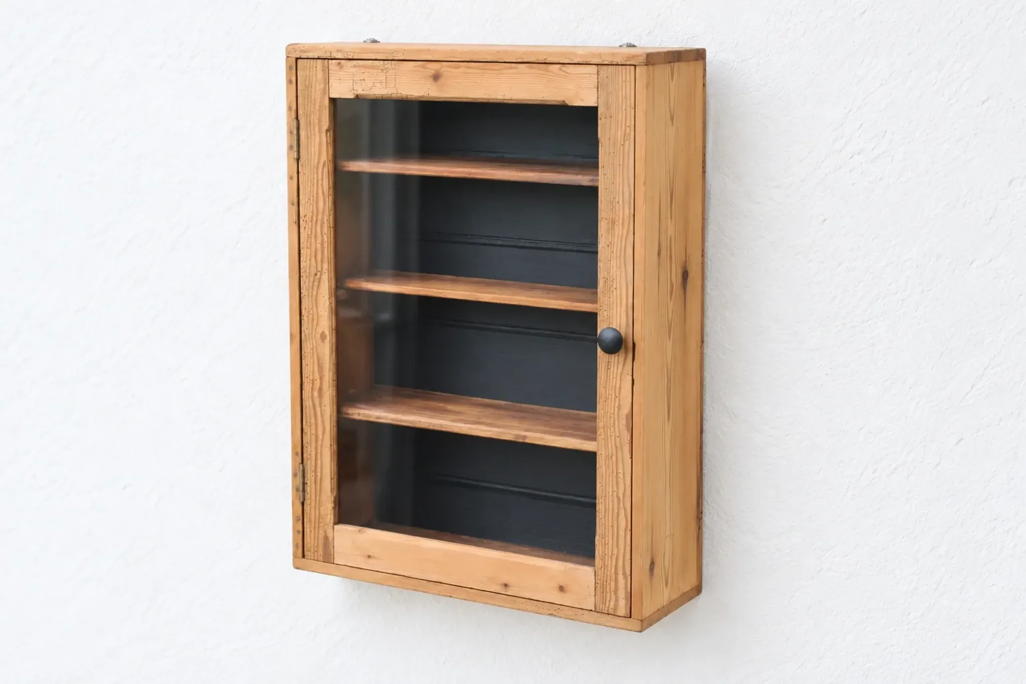 Antique wall display cabinet in natural wood and black – small glass-fronted collector's piece.