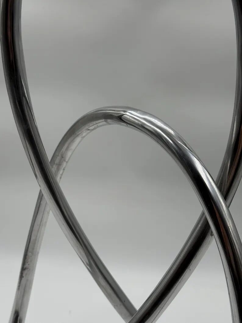 Chromed sculptural art object, abstract modernist shape in metal, contemporary design accent, brutalist interior decoration.