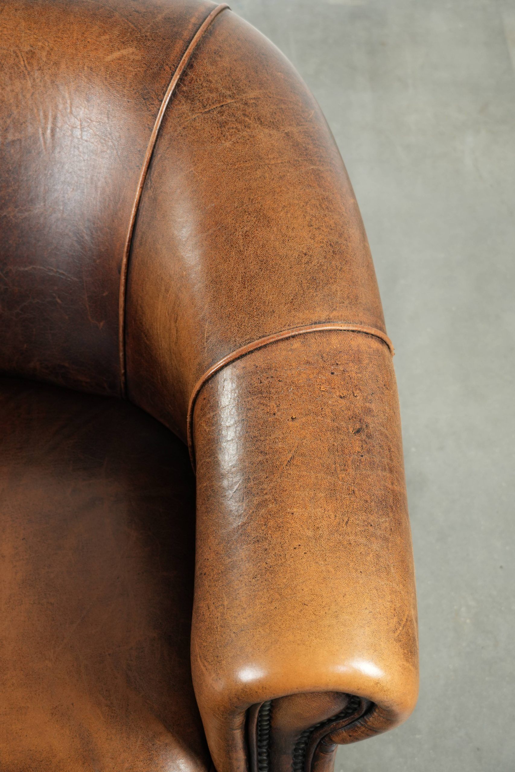 Fauteuil club en cuir de peau de mouton avec un coussin de siège fixe.