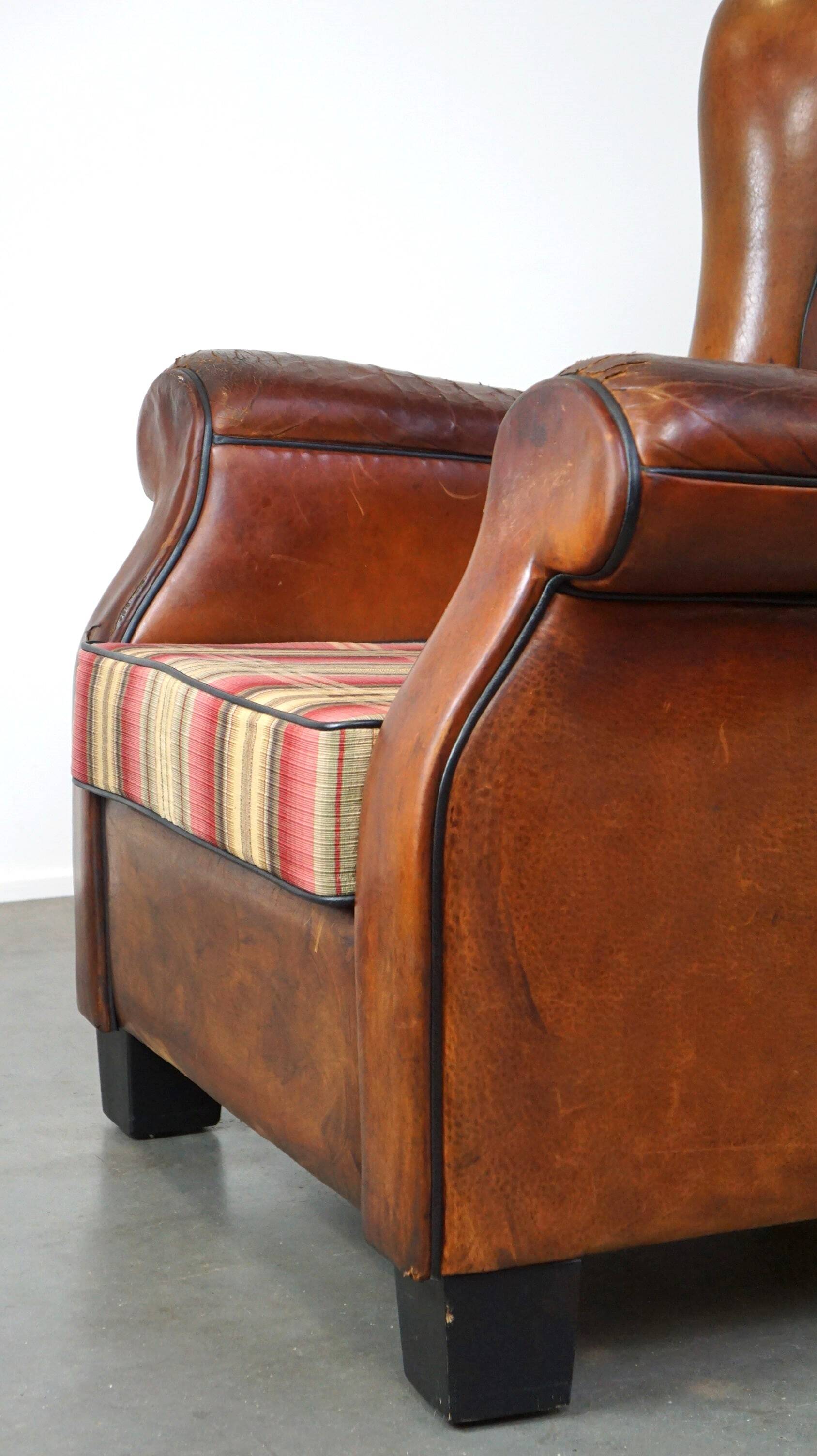 Very large worn sheepskin wing chair with a checked seat cushion