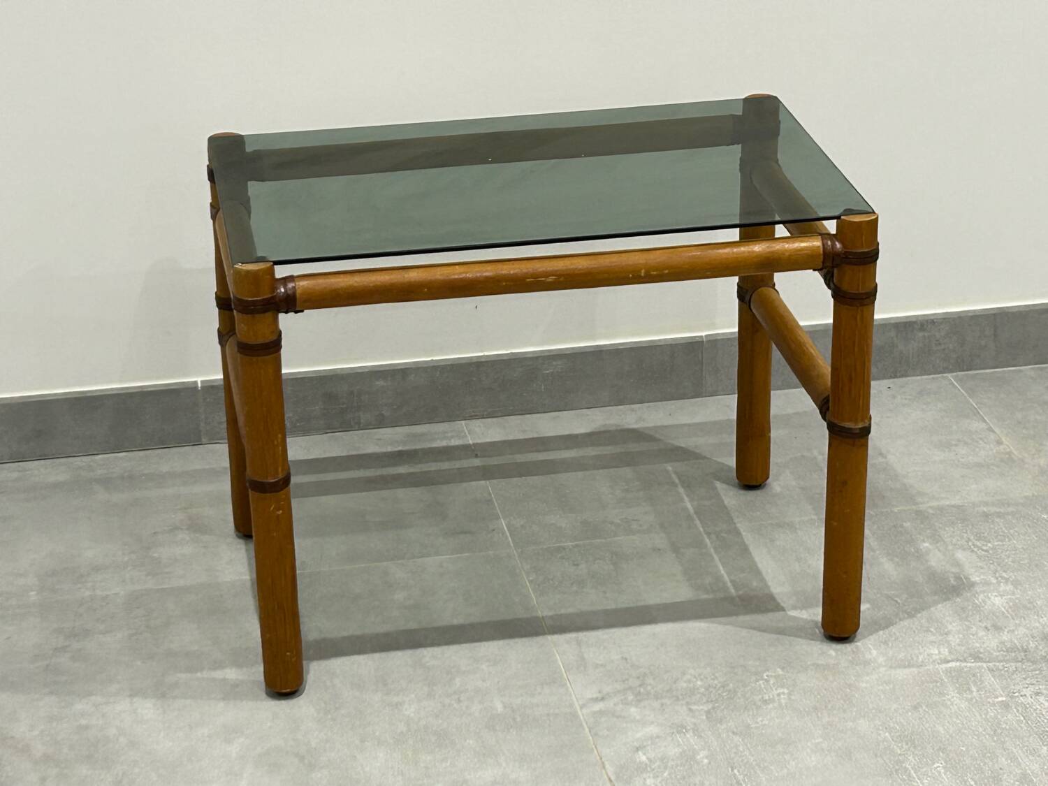 Blonde wood coffee table with smoked glass and leather bindings.