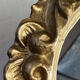 Round wooden mirror in golden colour.