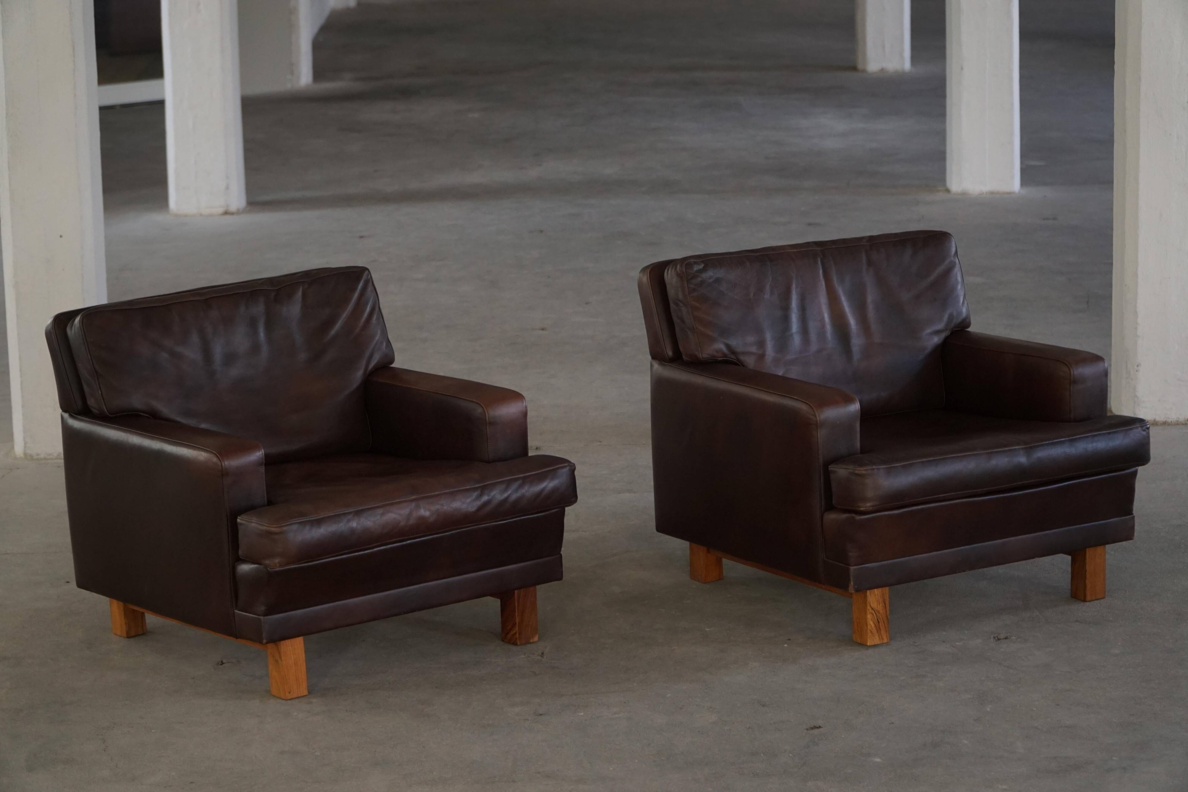 Pair of modern Danish lounge chairs in dark brown leather and rosewood, 1960s.