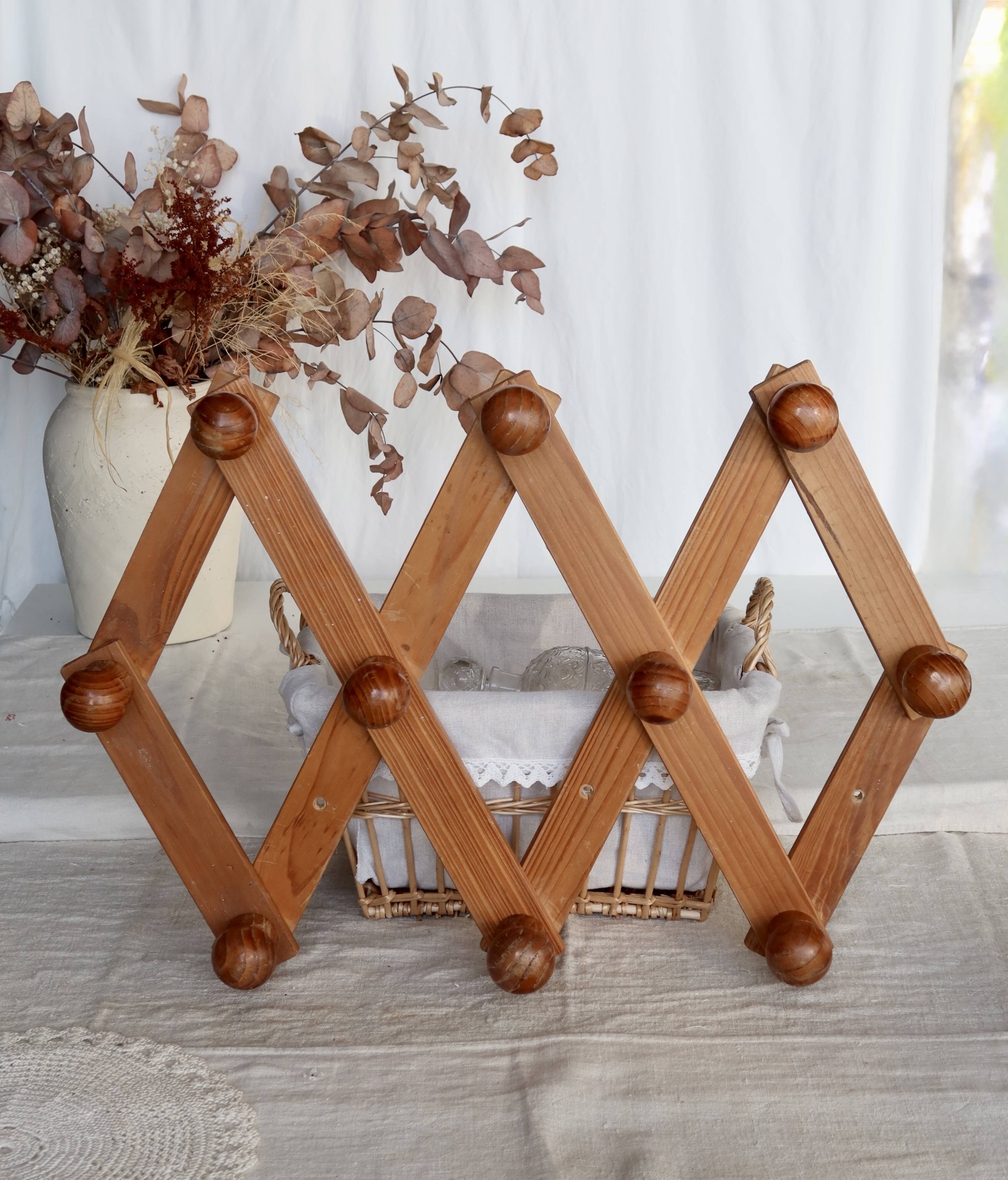 Antique wall-mounted coat rack accordion in dark pine, 10 wooden hooks.