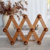 Antique wall-mounted coat rack accordion in dark pine, 10 wooden hooks.