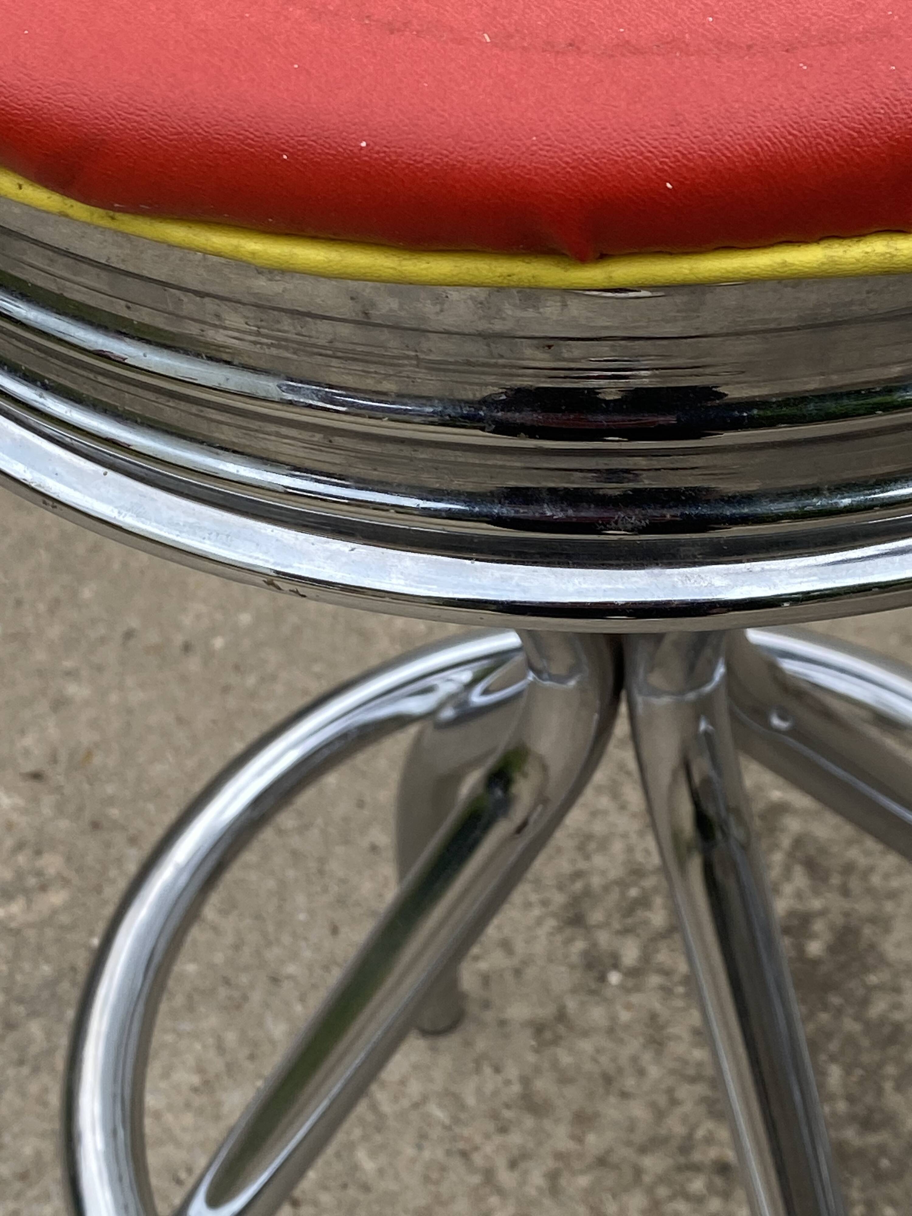 Set of 5 vintage swivel bar stools in blue, red, orange, and yellow.