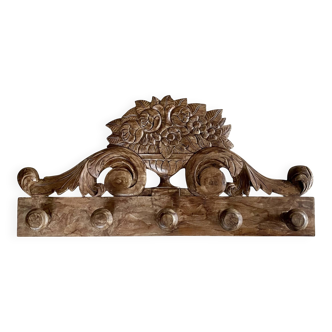 Wall-mounted coat rack on a carved wooden pediment