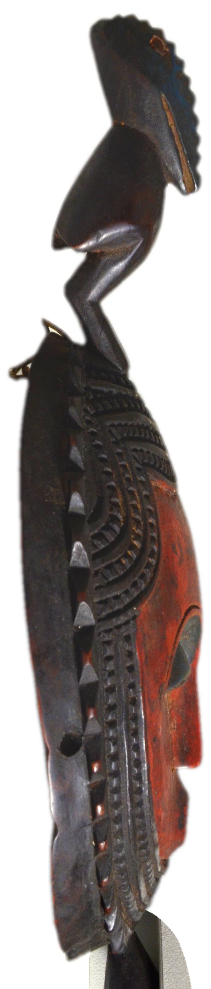 African wooden mask, face topped with a bird.