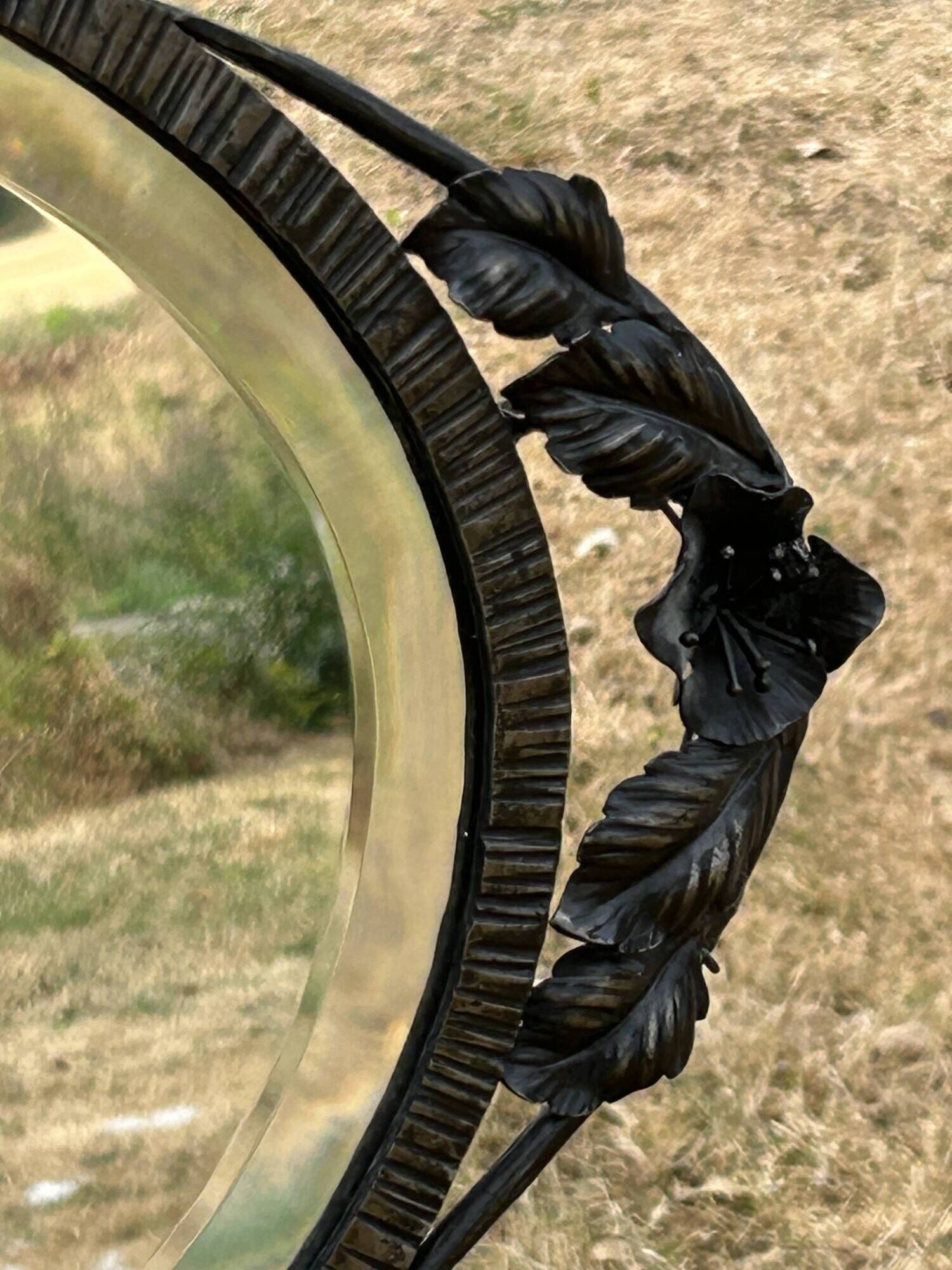 Bevelled oval mirror, richly crafted Art Deco wrought iron.