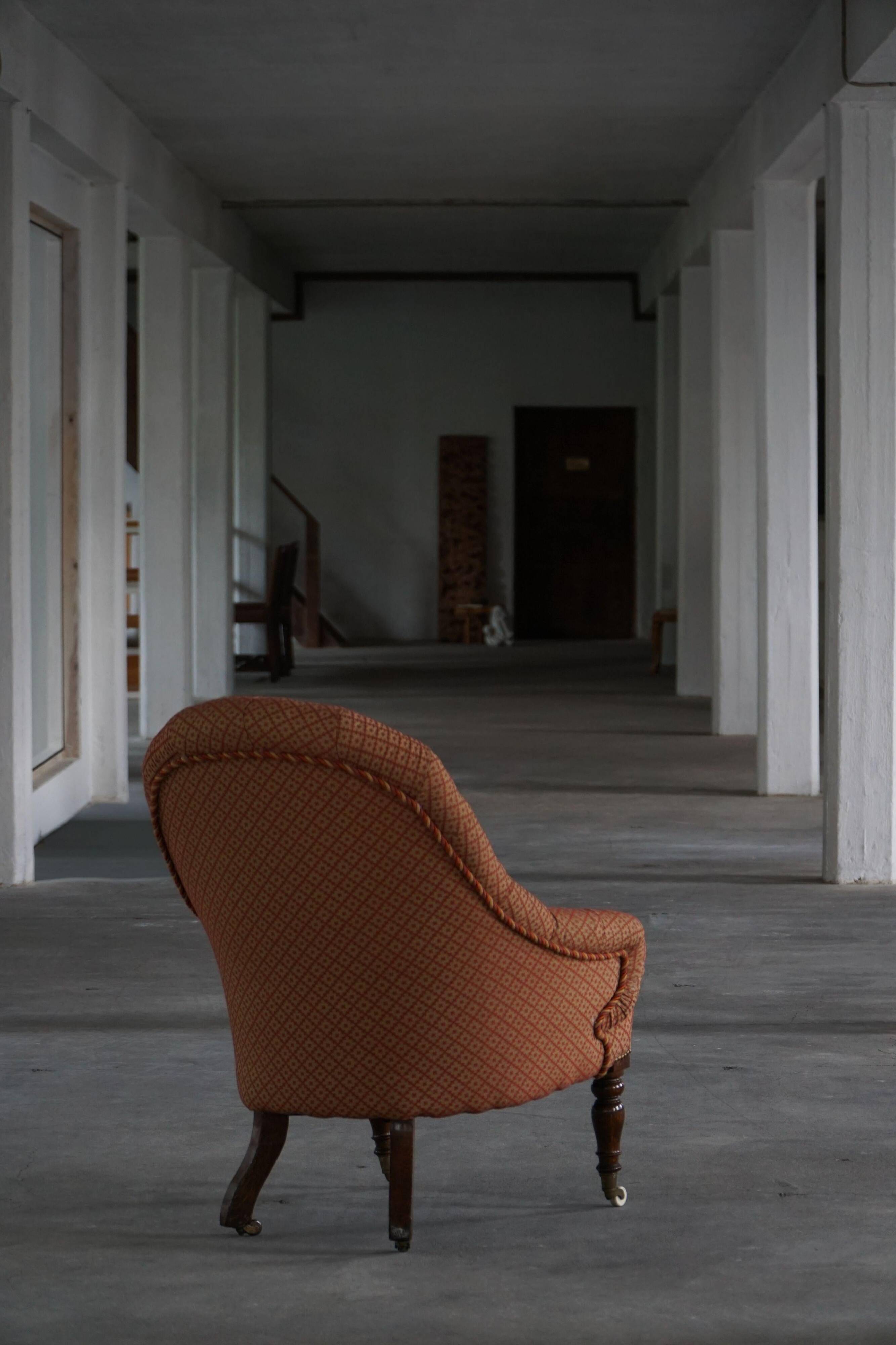 Victorian mahogany armchair, with wheels and coloured fabric, England, early 1900s.