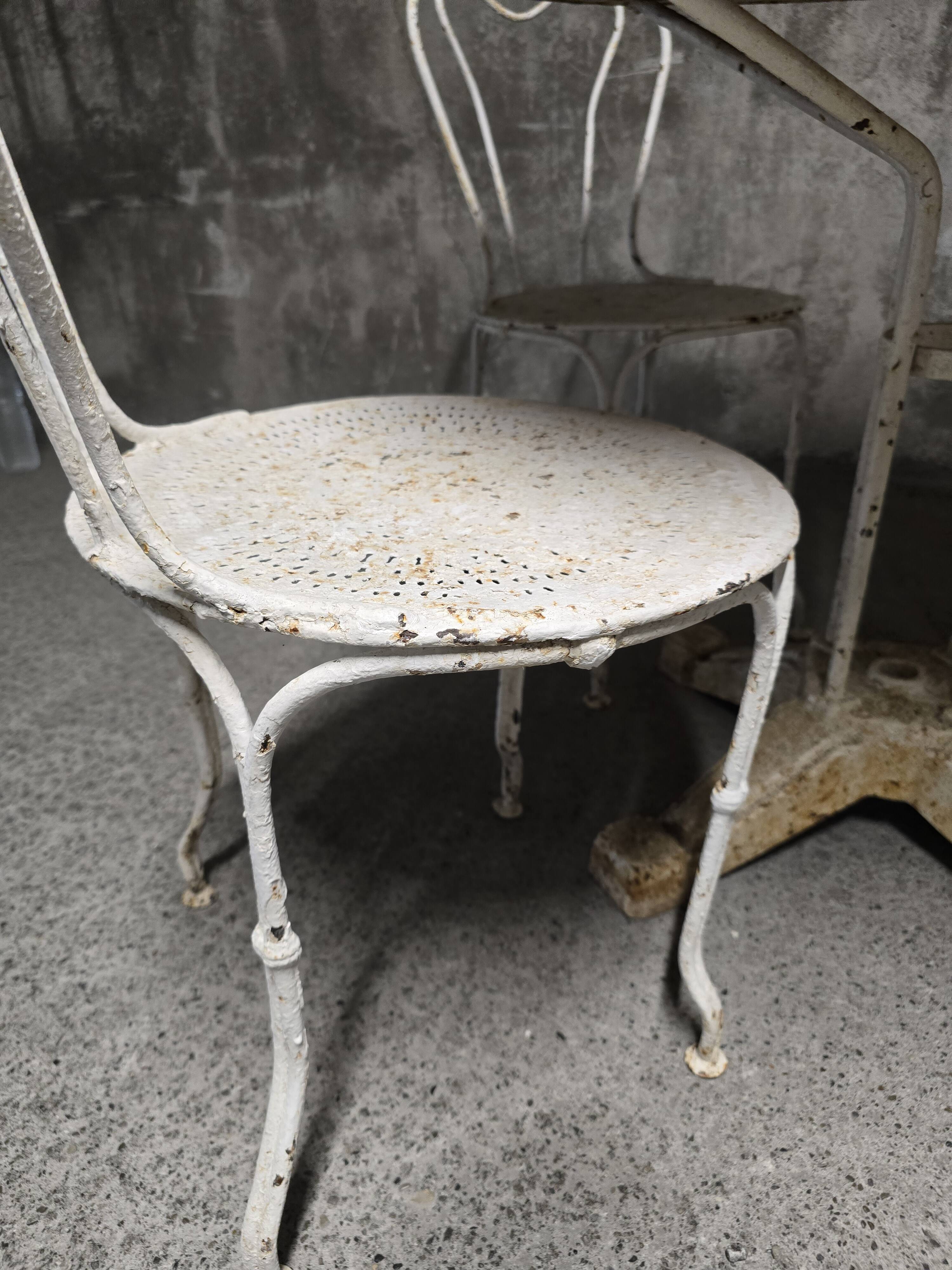 Antique painted wrought iron garden furniture, round table and four chairs.