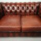Two-seater brown leather chesterfield sofa
