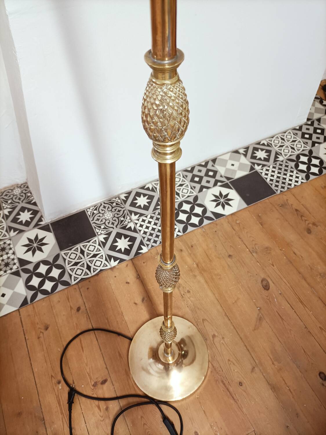 Bronze floor lamp with pine cone decoration.