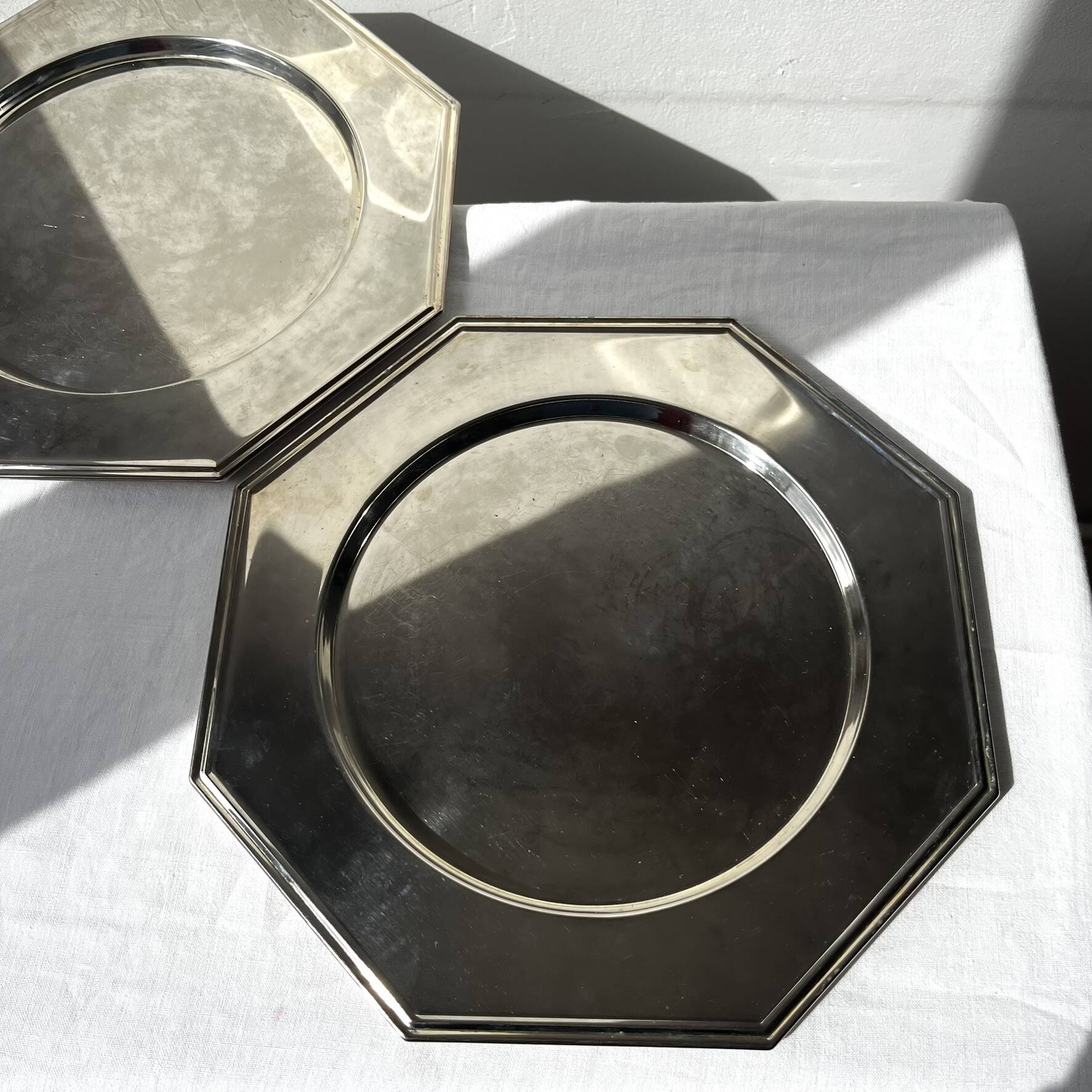 Many octagonal presentation plates in silver-plated metal.