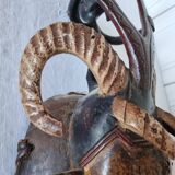 A large Senufo mask made of colored wood, decorated with an anthropomorphic figure