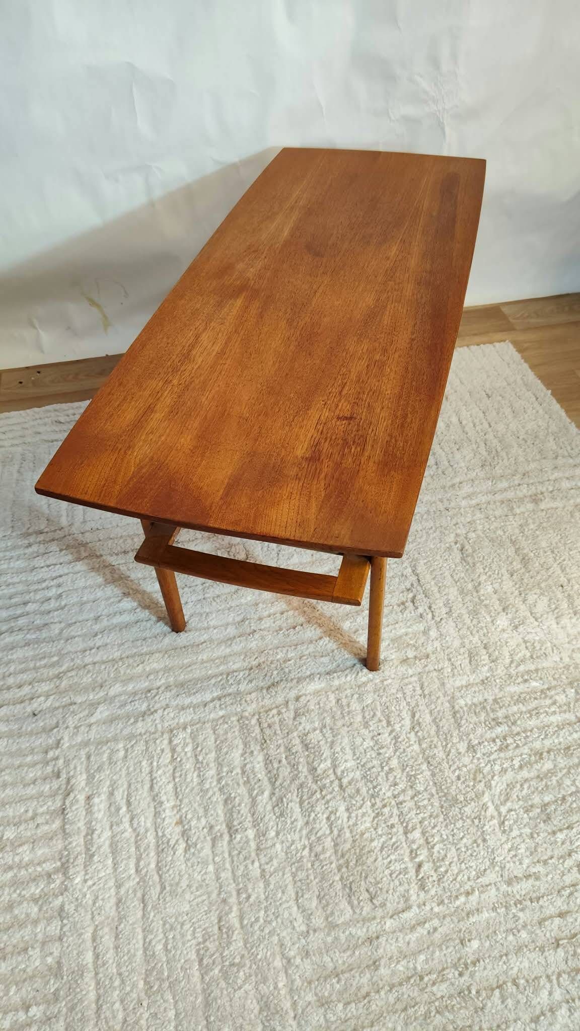 Scandinavian coffee table in teak with a lower shelf and brass bars.