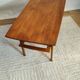 Scandinavian coffee table in teak with a lower shelf and brass bars.
