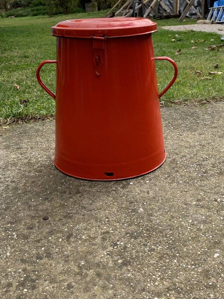 Red enamelled metal bin from the 1950s, with a lockable lid and side handles.