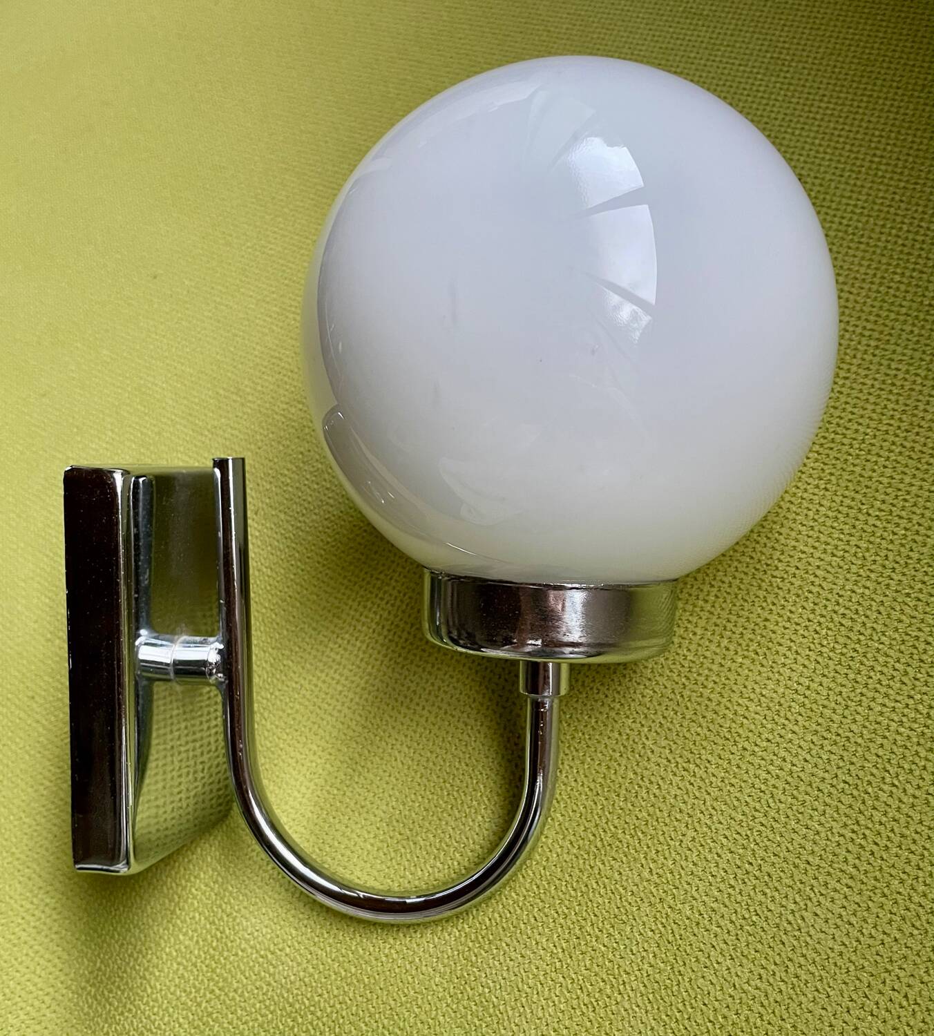 Pair of chrome metal wall lights with white glass globe.