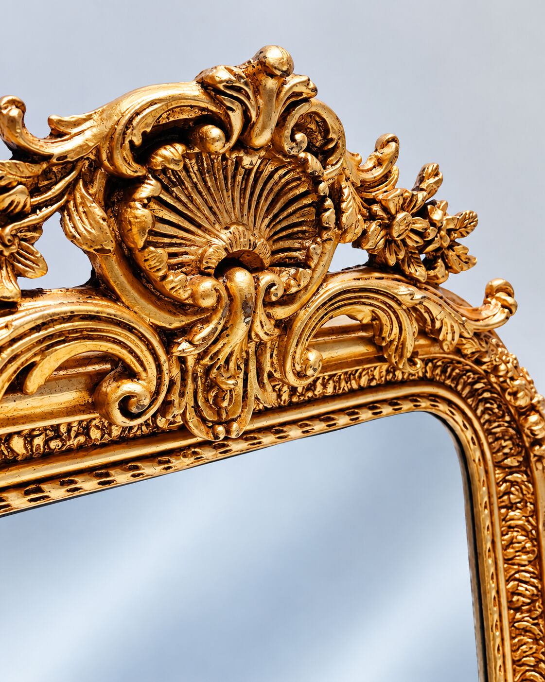 Grand miroir baroque en or avec un crête orné.