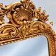 Grand miroir baroque en or avec un crête orné.