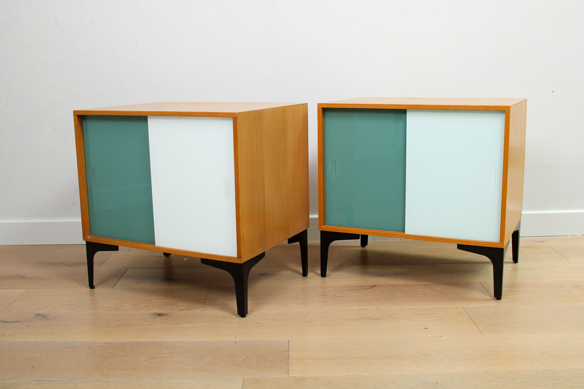 A pair of vintage mid-century bedside tables with glass sliding doors
