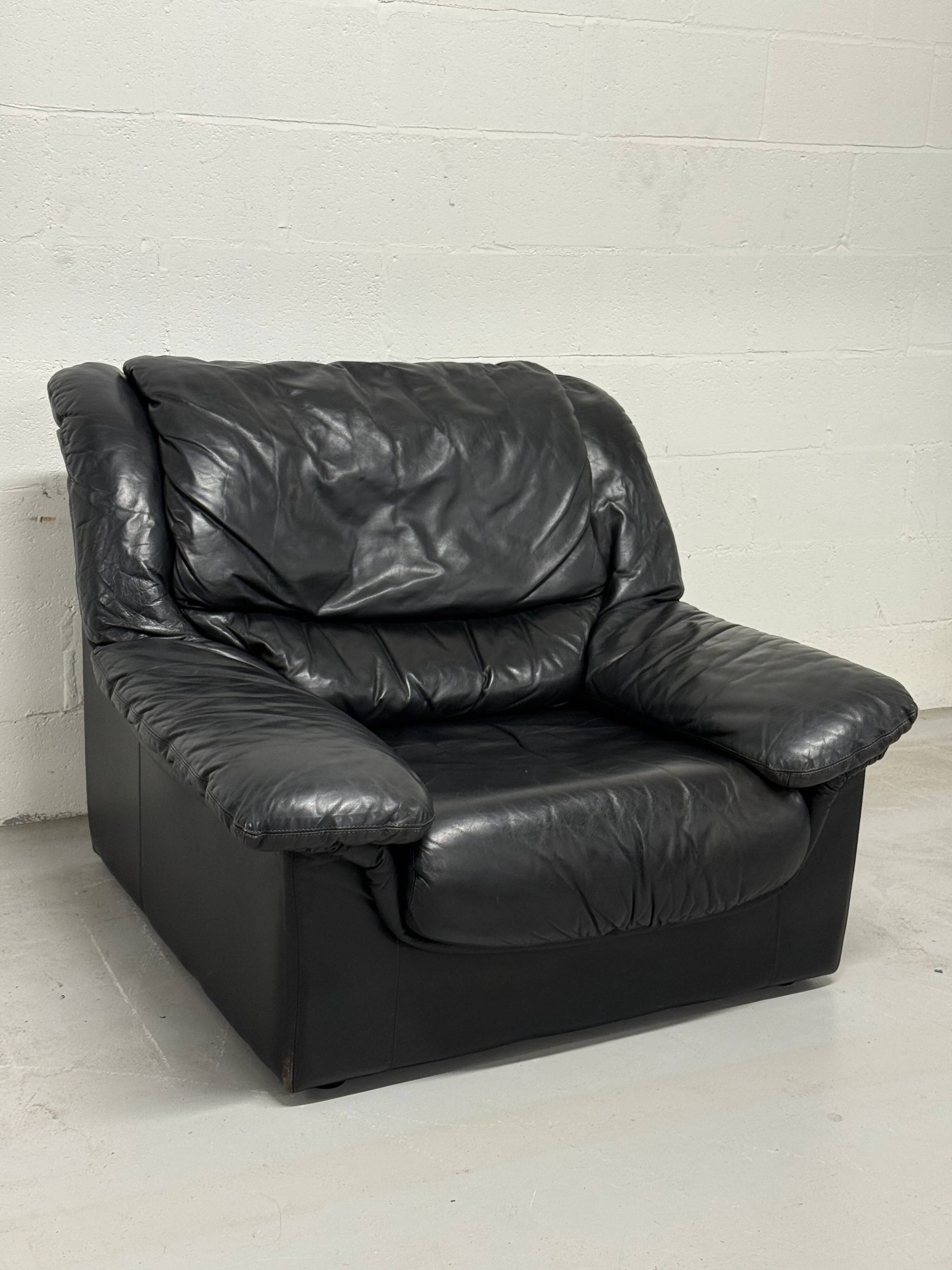 Vintage black leather lounge chair — low postmodern club chair from the space age.