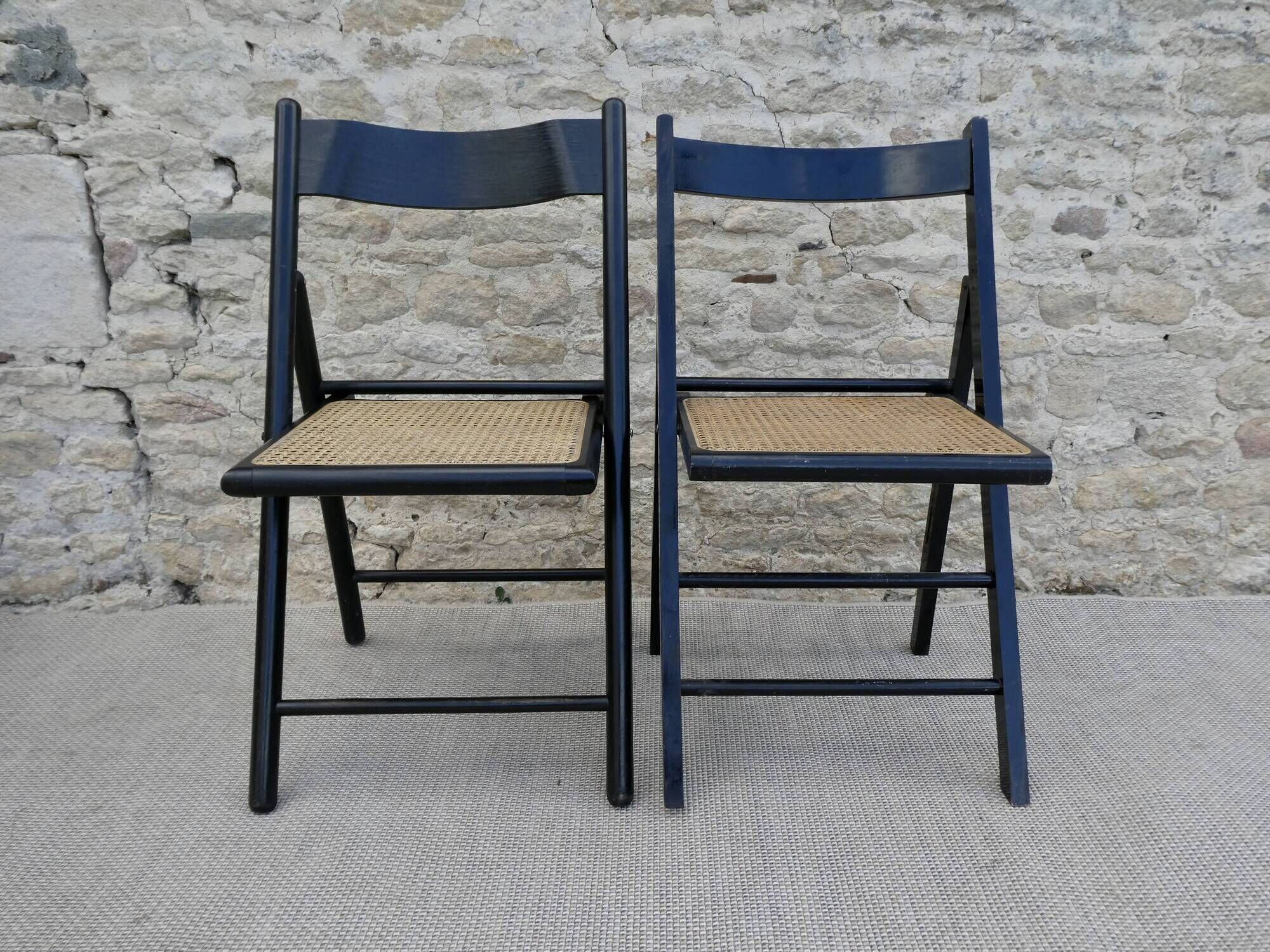 Paire de chaises pliantes en bois noirci et assise cannée