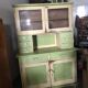 Vintage wooden kitchen cupboard painted green and beige, with glass doors - 1930s