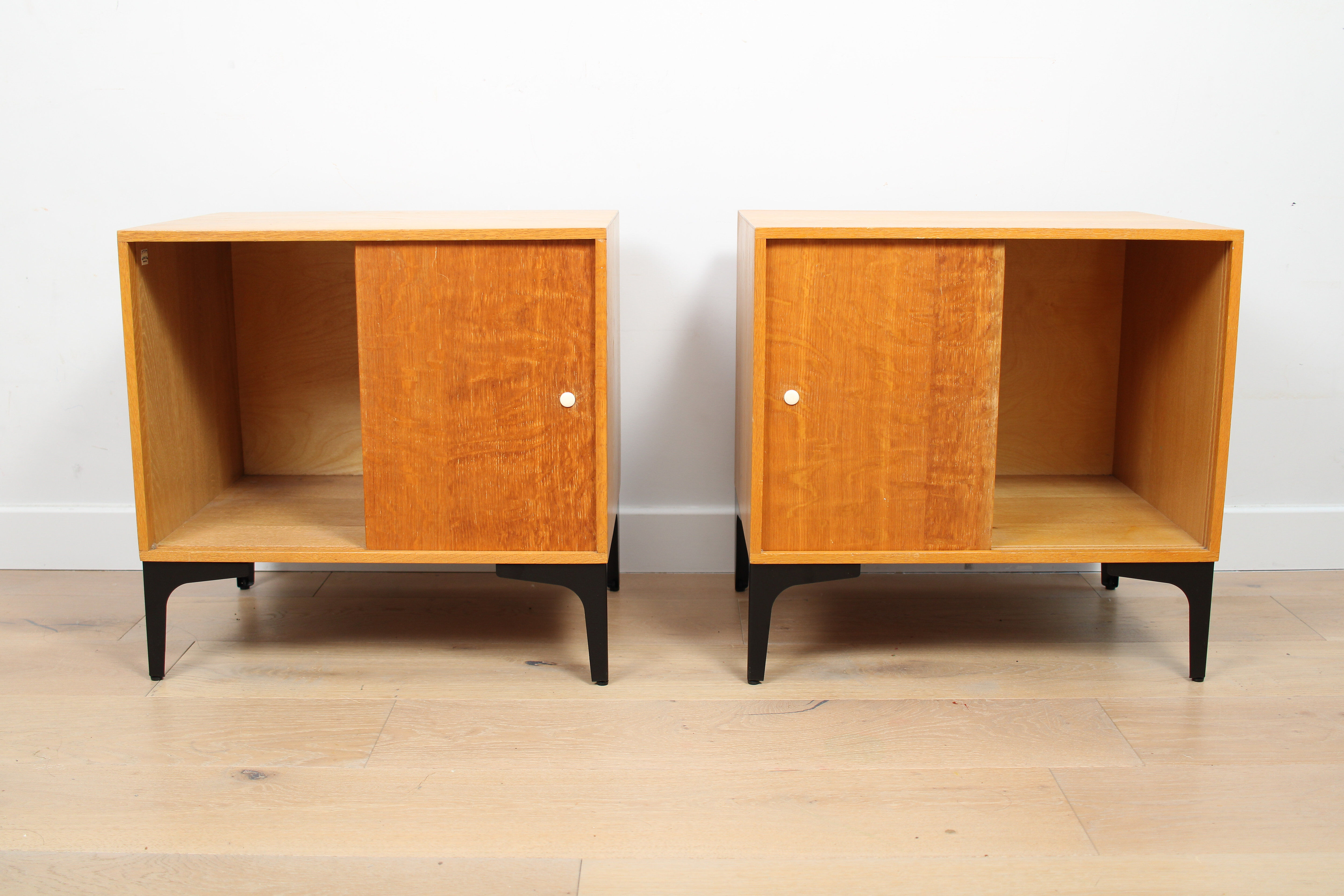 A pair of vintage mid-century bedside tables with oak sliding doors