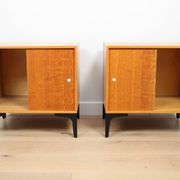 A pair of vintage mid-century bedside tables with oak sliding doors