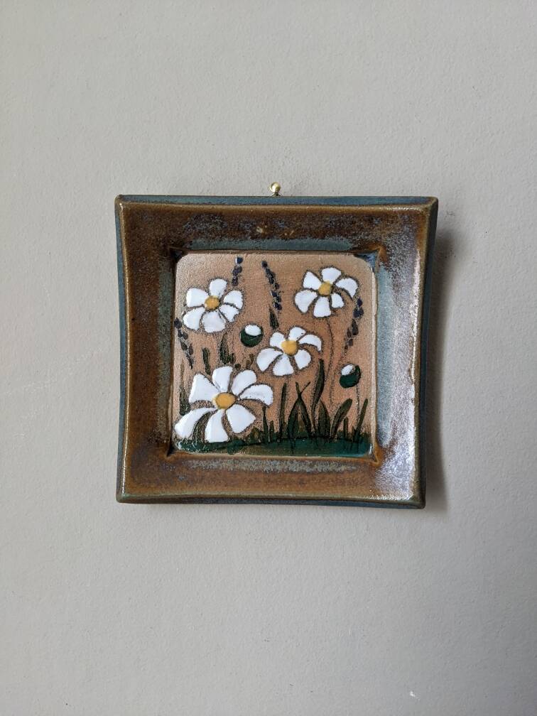 Handcrafted ceramic wall hanging with floral daisy decoration