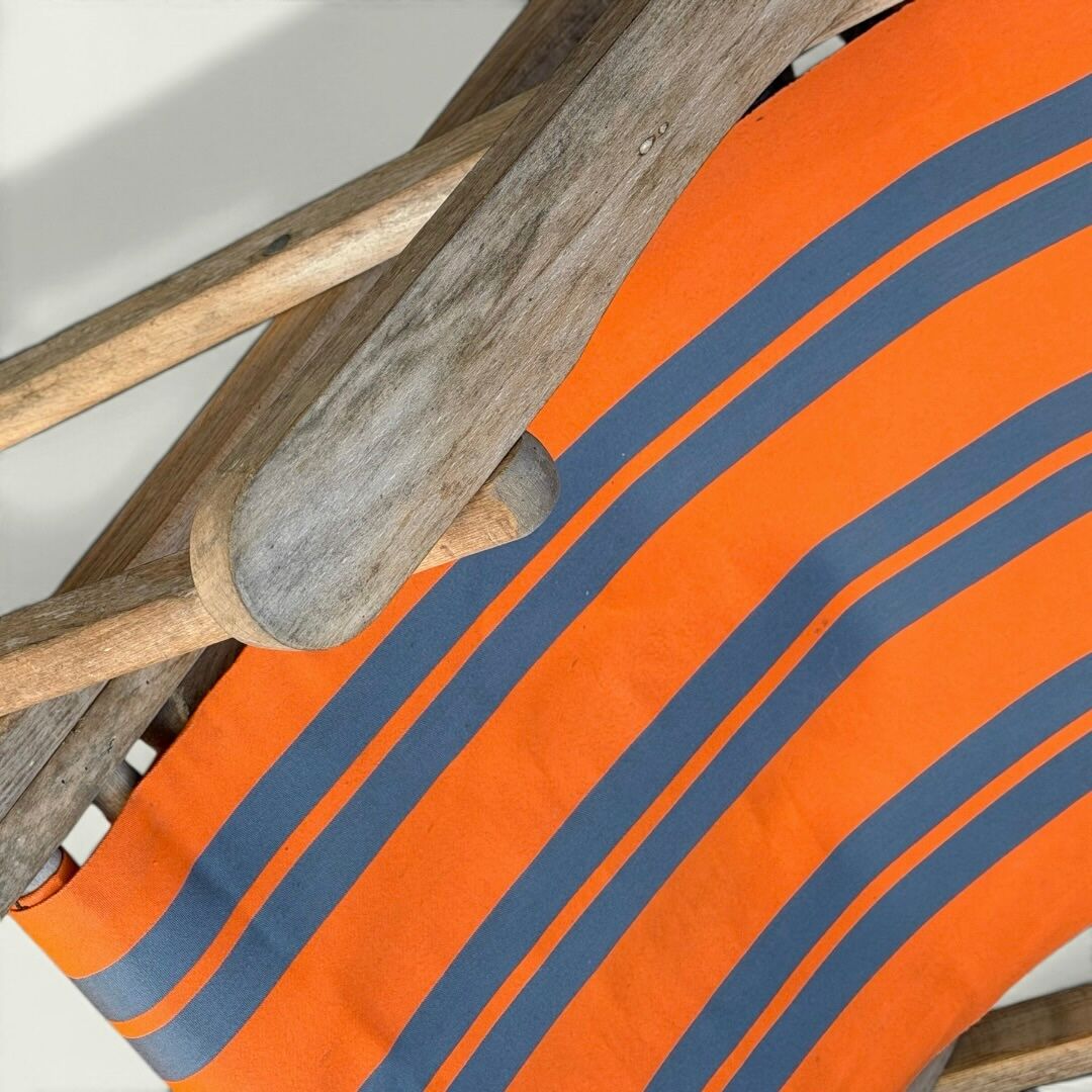 Vintage deck chair with orange and grey striped fabric, original patina.